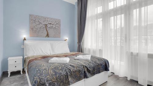 Aphrodite Suite Hotel Karlovy Vary في كارلوفي فاري: غرفة نوم بسرير ونافذة كبيرة