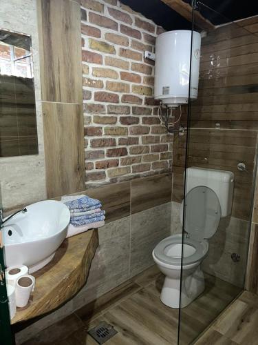 a bathroom with a sink and a toilet and a brick wall at Chalet Etno Oaza near Airport in Sarajevo