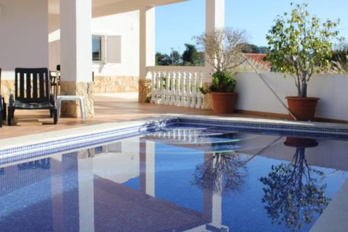 a swimming pool in a backyard with a chair at Villa Carpe Diem (Seize the day) in Carvoeiro