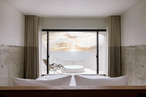 a bedroom with a window with a view of the ocean at Izumo HOTEL THE CLIFF 