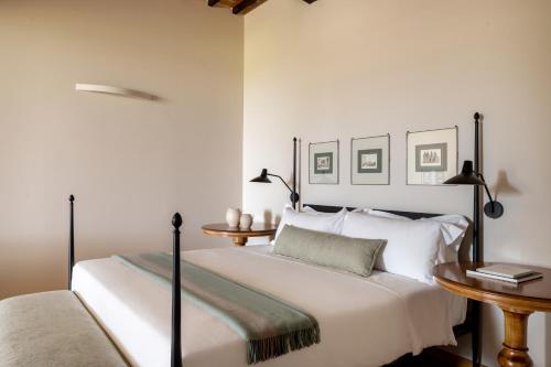 a white bedroom with a bed and two tables at Precise Tale Poggio Alla Sala in Montepulciano