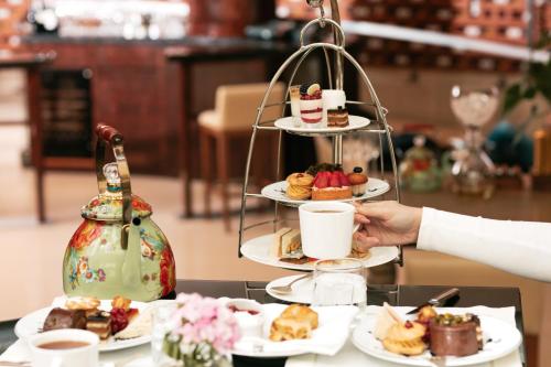 eine Person hält eine Tasse und ein Tablett mit Desserts in der Unterkunft Park Hyatt Istanbul - Macka Palas in Istanbul