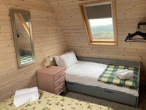 a small bedroom with a bed and a window at Hedgehog Glamping Pod School House Farm in Leighton