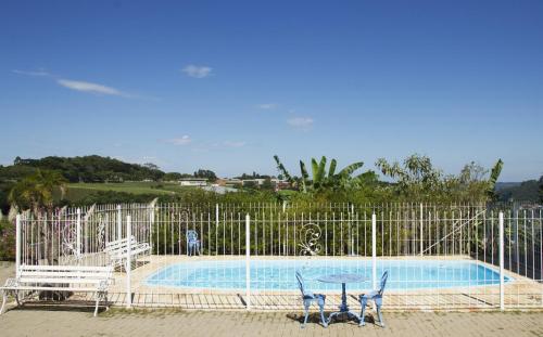 een hek met twee stoelen en een zwembad bij Hotel Villa Deifiori in Bento Gonçalves