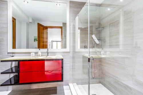 Un baño con un lavabo rojo y una ducha. en Villa Cavall, en Cala de Sant Vicent