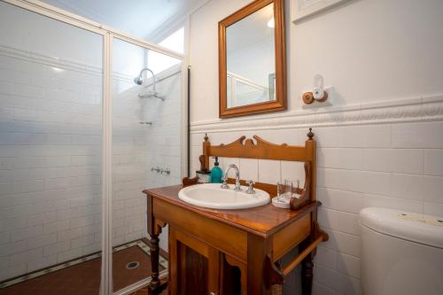 La salle de bains est pourvue d'un lavabo, d'un miroir et de toilettes. dans l'établissement Cosy coastal cottage- Allwood Harbour, à Kiama