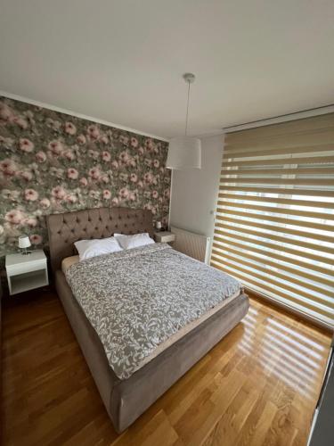 a bedroom with a bed with a floral wall at Apartman M&M in Doboj