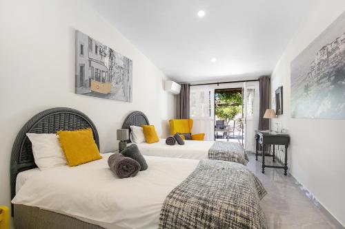 two beds in a bedroom with yellow pillows at Quinta Aida Cottage and B&B Suites in Lagoa