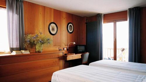 a bedroom with two beds and a desk with a television at La Trinitè Monboso Hotel in Gressoney-la-Trinité