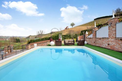 a large swimming pool with blue water in a yard at B&B La Dolce Vita in Priocca