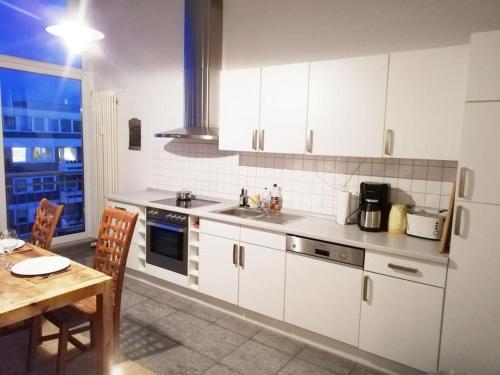 une cuisine avec des placards blancs, une table et une fenêtre dans l'établissement Penthousewohnung 126 qm Bremen Innenstadt+ Dachterrasse, à Brême