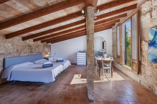 a bedroom with a bed and a table in a room at Es Garroverar in Pollença