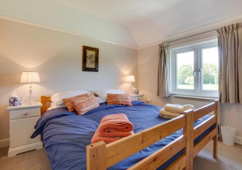 - une chambre avec un lit doté de draps bleus et une fenêtre dans l'établissement Penhill Cottage, à Saint Michaels