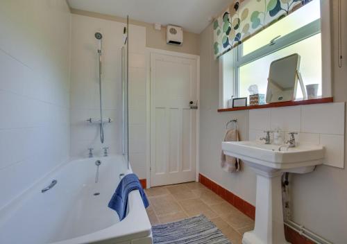 La salle de bains est pourvue d'une baignoire, d'un lavabo et d'un miroir. dans l'établissement Penhill Cottage, à Saint Michaels