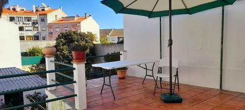 a table and chairs on a balcony with an umbrella at Casa da Forja in Pinhal Novo