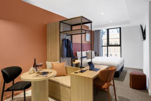 um quarto de hotel com uma cama, uma secretária e uma mesa em Quest Collingwood em Melbourne