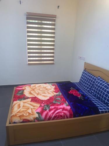 a bedroom with a bed with a flower quilt on it at Modern Bungalow in Idi Aba in Abeokuta