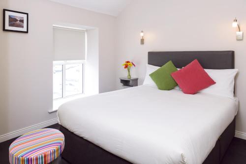 een slaapkamer met een groot wit bed met kleurrijke kussens bij Dan Linehans Bar and B&B in Killarney