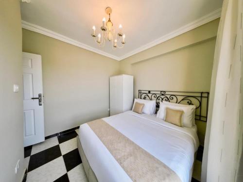 a bedroom with a large white bed with a chandelier at Downtown Sea View Suites in Alexandria