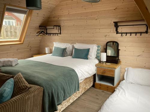 a bedroom with two beds and a mirror at Owl Glamping Pod in Leighton