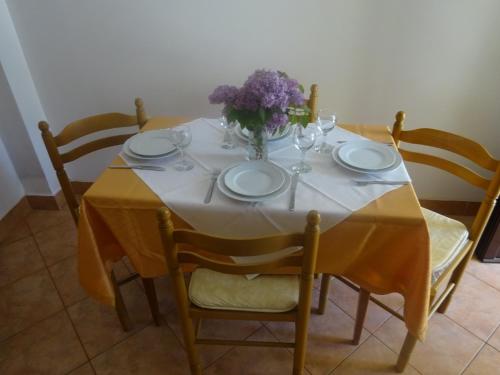 a table with plates and a vase of flowers on it at Apartment and Rooms Milena in Mošćenička Draga