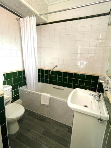 a bathroom with a toilet and a tub and a sink at The Continental Hotel, Derby in Derby
