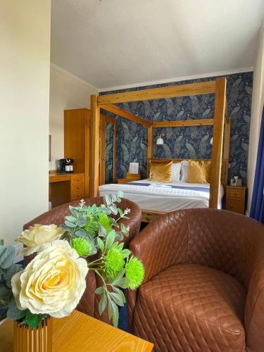 a hotel room with a bed and a couch and flowers at The Continental Hotel, Derby in Derby