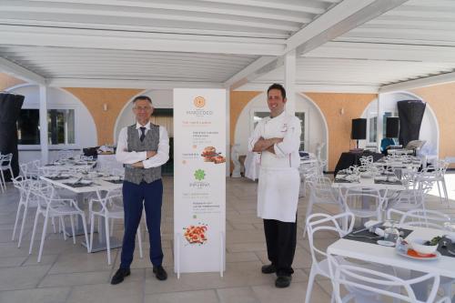 two men standing next to a sign in a room with tables at Hotel Parco Delle Agavi in Ischia