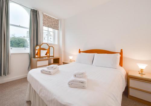 een slaapkamer met een groot wit bed en handdoeken bij Kemp Town Mews in Brighton & Hove