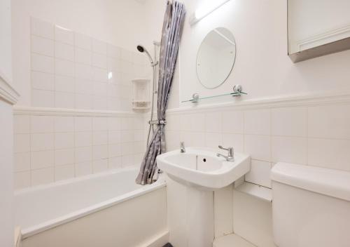 a white bathroom with a sink and a mirror at Kemp Town Mews in Brighton & Hove