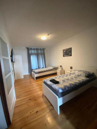 a bedroom with two beds and a wooden floor at Monteurzimmer Pavan IK1 , Apartment for Workers Saarlouis Saarbrücken Überherrn - KEINE Ferienwohnung in Saarlouis