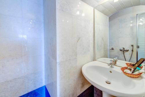 a white bathroom with a sink and a mirror at Apollonion Palace in Ermoupoli