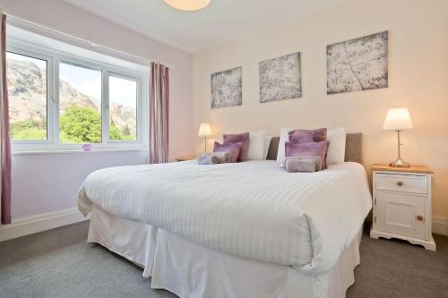 een slaapkamer met een groot wit bed met paarse kussens bij Green Croft Coniston in Coniston
