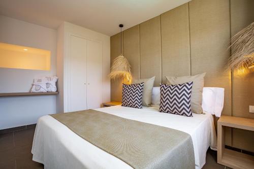 een slaapkamer met een groot bed met kussens erop bij Migjorn Ibiza Suites & Spa in Playa d'en Bossa