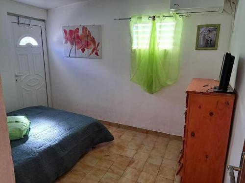 a bedroom with a bed and a television on a dresser at location Maison Basse-Terre GUADELOUPE in Basse-Terre