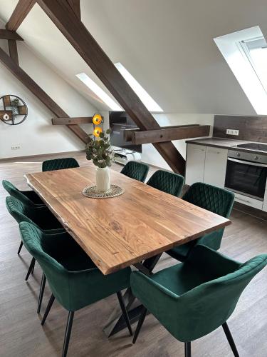 a dining room with a wooden table and green chairs at Dachterrassenwohnung Katharinenschule in Eisenach