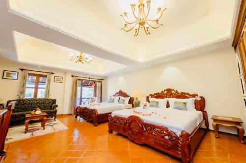 a bedroom with two beds and a couch and a chandelier at Villa Deux Rivieres双河别墅酒店 in Luang Prabang