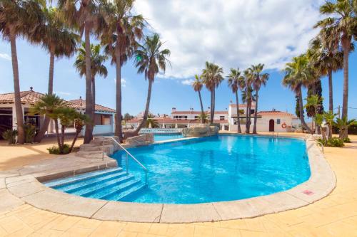 a swimming pool with palm trees in a resort at Siesta Mar Private Apartment 83 Cala'n Porter 1 bed in Cala'n Porter