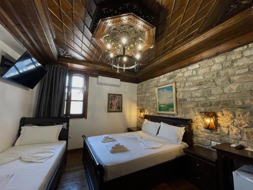 a bedroom with two beds and a stone wall at White House Berat in Berat