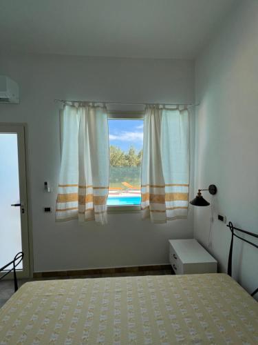 ein Schlafzimmer mit einem Bett und ein Fenster mit einem Pool in der Unterkunft Casa vacanze Mare Fuori in Capoterra