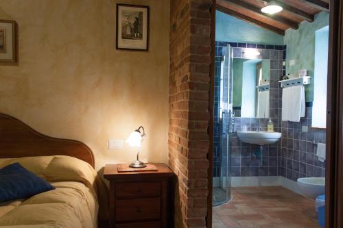 a bedroom with a bed and a bathroom with a sink at B&B Le Caselle "Il Baraccotto" in Lucignano