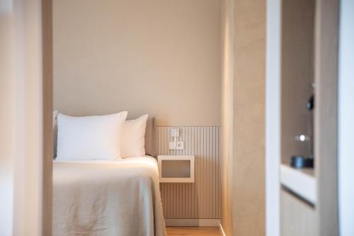 Cette chambre comprend un lit avec des draps blancs et une télévision. dans l'établissement Hotel Bommelje, à Domburg