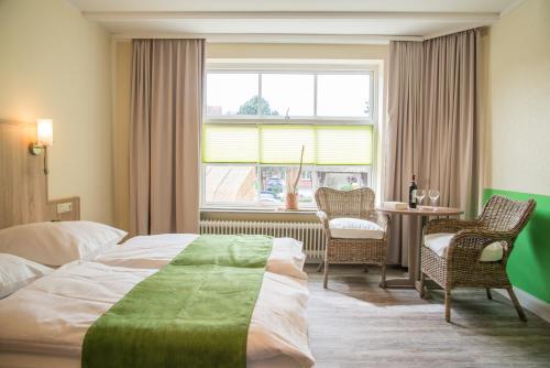 a hotel room with a bed and a table and a window at Dünen Stuuv in Sankt Peter-Ording