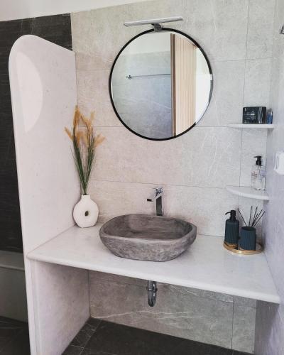 a bathroom with a stone sink and a mirror at Evangelia's Cozy House in Ermoupoli