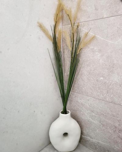 a white vase with a plant in it at Evangelia's Cozy House in Ermoupoli