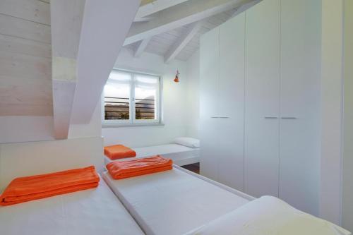 een witte kamer met 2 oranje kussens op de vloer bij Residenza ai Ferrari - Appartamento Lilium in Riva del Garda