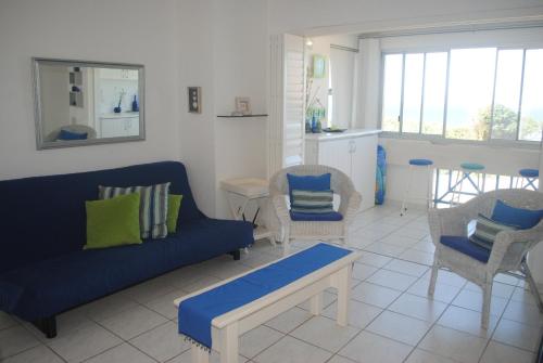 ein Wohnzimmer mit einem blauen Sofa und Stühlen in der Unterkunft 37 Key Largo in Kingsborough