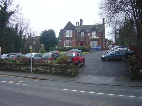 a parking lot with cars parked in front of a house at The Hill Hotel in Dumfries