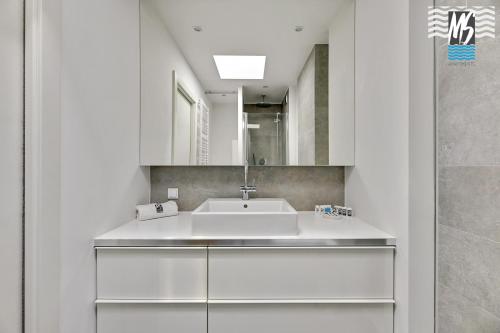 Baño blanco con lavabo y espejo en MS Apartments Green Hill I, en Gdynia