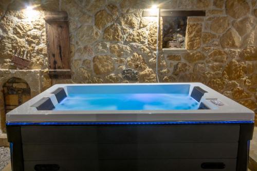 een hot tub met blauwe verlichting in een stenen badkamer bij Pamelas House with Jacuzzi in Kissamos